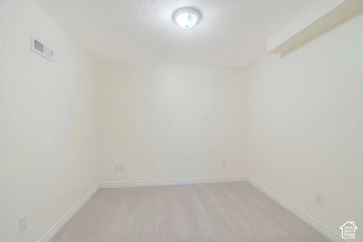 Neutral-toned room featuring light beige carpeting and white baseboards