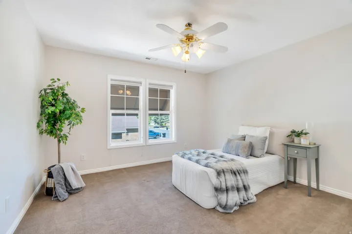 Carpeted room featuring a ceiling fan with integrated lighting, two windows with white trim, and light-toned walls