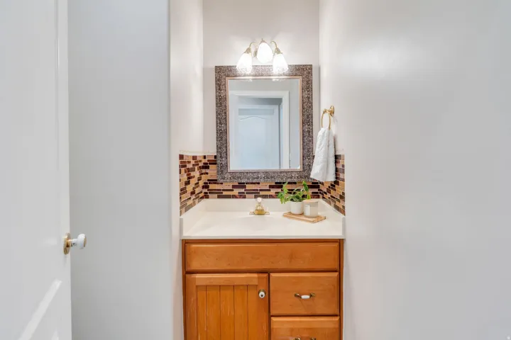 Vanity featuring a light wood-finish cabinet with paneling and drawers, a light-toned countertop, and a mosaic tile backsplash
