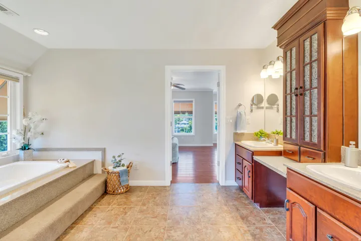 Bathroom featuring a built-in soaking tub with carpeted steps, a window with natural light, and recessed lighting