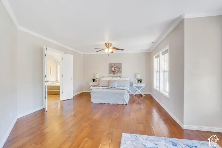 Spacious room featuring wood-finish flooring, white crown molding, and a ceiling fan