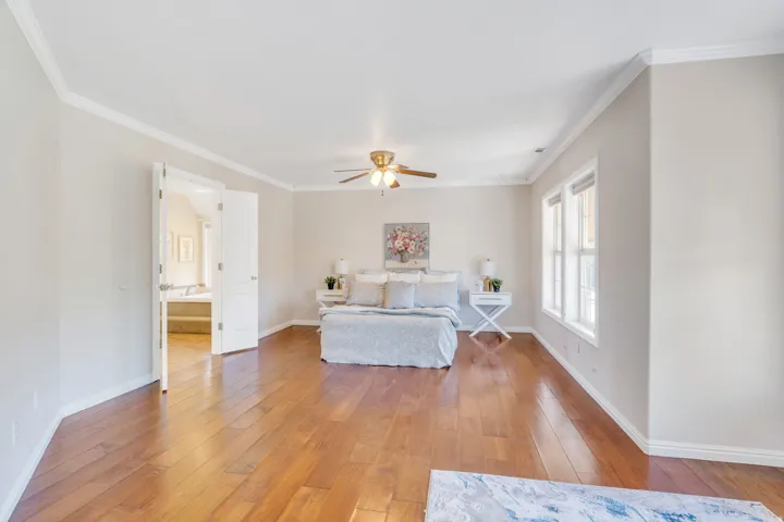 Spacious room featuring wood-finish flooring, white crown molding, and a ceiling fan