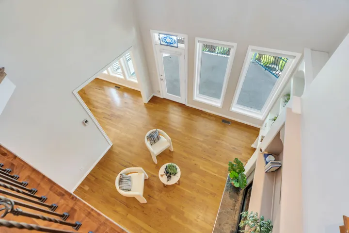 Vaulted ceiling interior featuring hardwood flooring, built-in shelving, a fireplace with a stone surround, and multiple tall windows