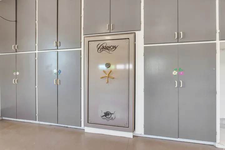 Integrated safe surrounded by extensive gray cabinetry with silver-tone hardware