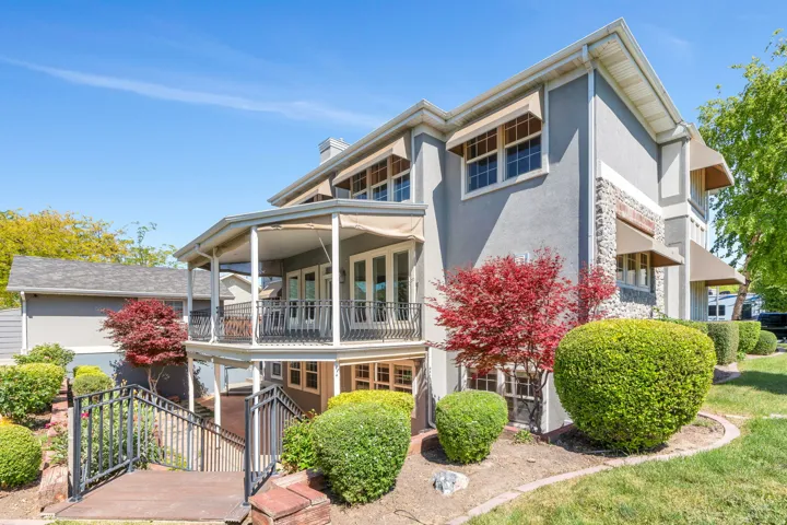 Stucco exterior featuring stone accents, multiple window awnings, and a two-story covered patio
