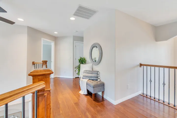 Upper-level hallway featuring wood-finish flooring, white baseboards, and light gray wall paint