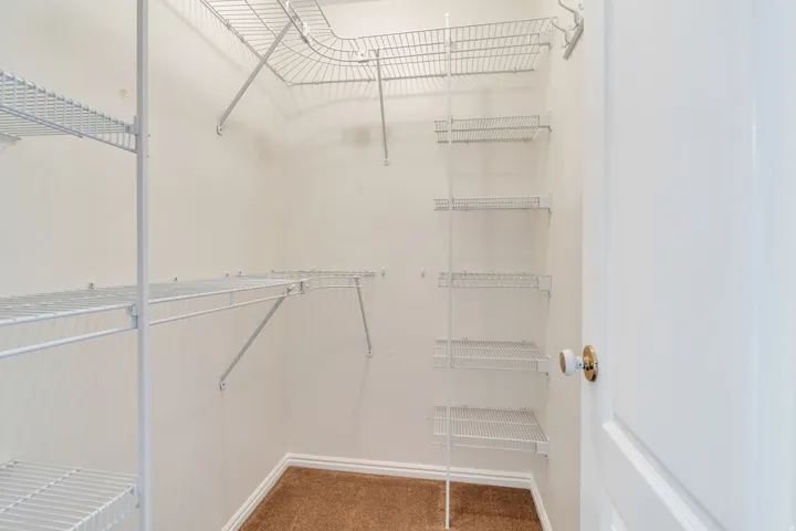 Closet featuring white wire shelving, hanging rods, and light brown carpeting