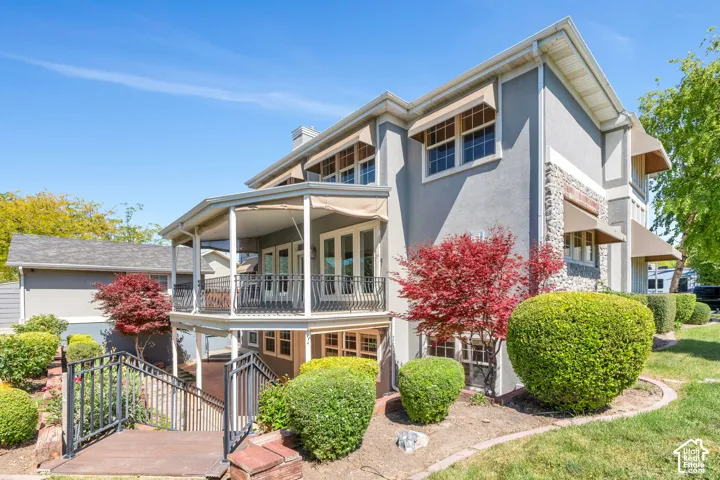 Stucco exterior featuring stone accents, multiple window awnings, and a two-story covered patio
