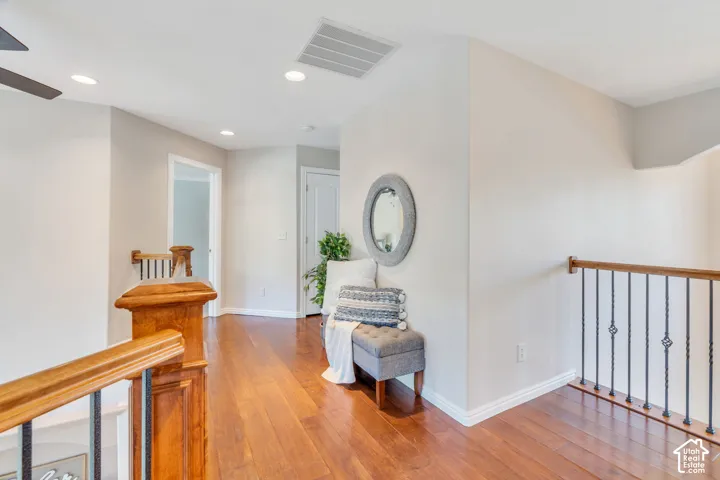 Upper-level hallway featuring wood-finish flooring, white baseboards, and light gray wall paint