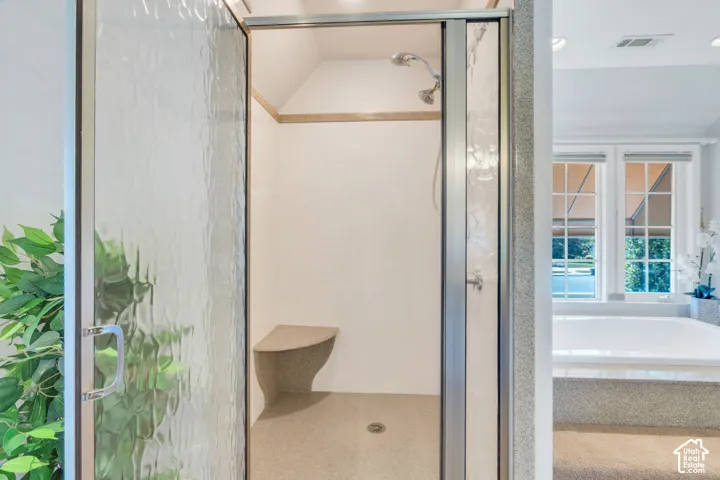 Walk-in shower with textured glass enclosure, built-in bench, and a dual-head shower fixture