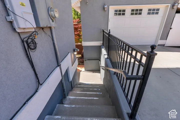 Concrete staircase with black metal railings descending alongside a stucco exterior