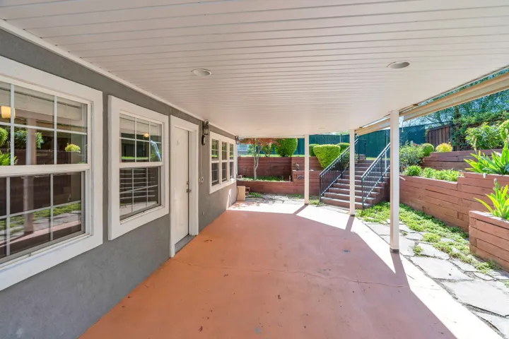 Covered patio featuring a concrete surface, recessed lighting, and access to a terraced garden with mature plantings and wood-finish retaining walls