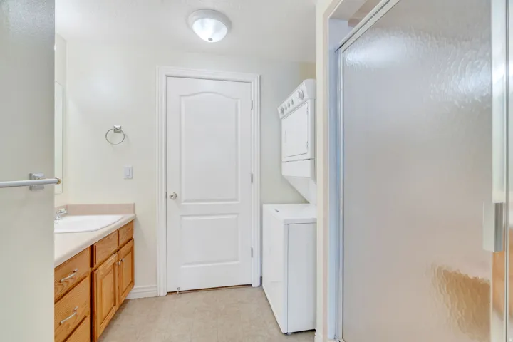 Bathroom featuring a wood-finish vanity with an undermount sink, a countertop, and a shower with a frosted glass door