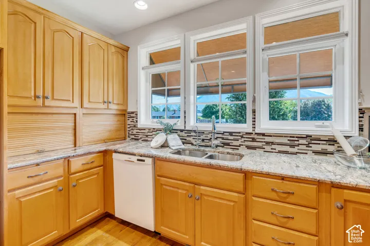 Kitchen featuring wood-finish cabinetry, light-toned stone countertops, and a mosaic tile backsplash