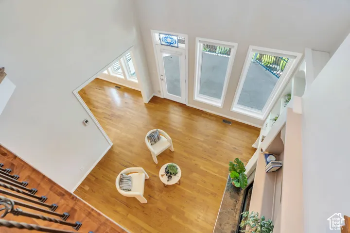 Vaulted ceiling interior featuring hardwood flooring, built-in shelving, a fireplace with a stone surround, and multiple tall windows
