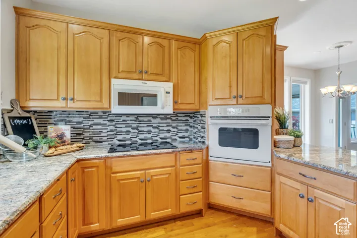 Kitchen with light wood cabinetry, granite countertops, a built-in oven, and a mosaic tile backsplash