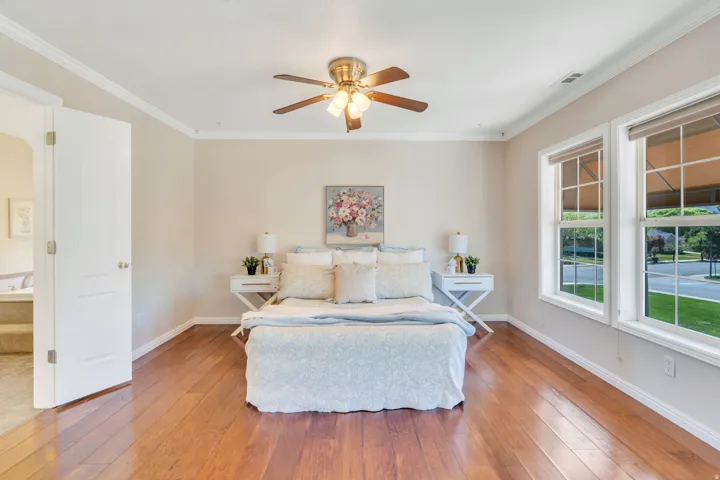 Spacious room featuring wood-finish flooring, crown molding, and a ceiling fan with integrated lighting