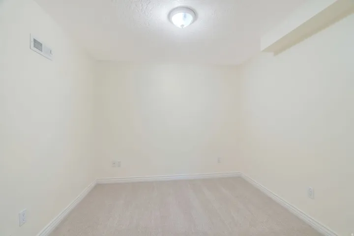 Neutral-toned room featuring light beige carpeting and white baseboards