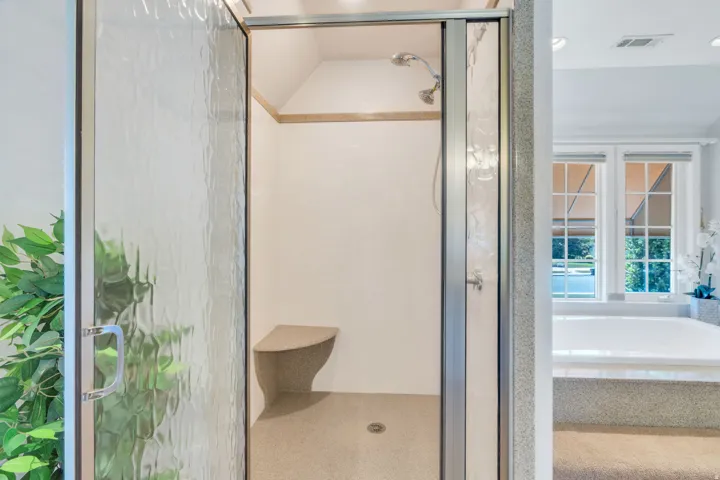 Walk-in shower with textured glass enclosure, built-in bench, and a dual-head shower fixture