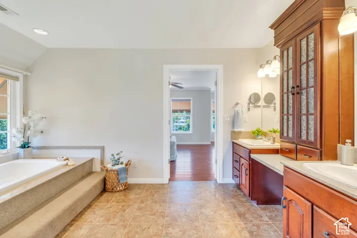 Bathroom featuring a built-in soaking tub with carpeted steps, a window with natural light, and recessed lighting