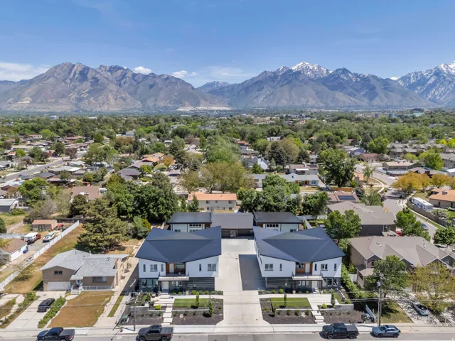 Modern architectural design featuring prominent mountain scenery, dark metal roofing, white exterior siding, and integrated landscaping