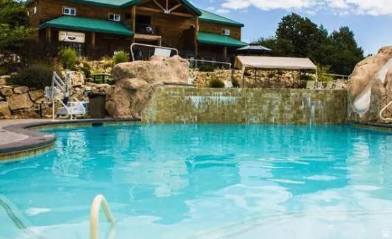 Swimming pool featuring a rock waterfall, integrated pool lift, and a surrounding stone hardscape