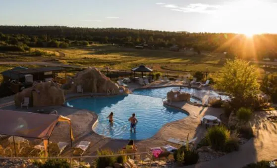 Expansive outdoor pool area featuring a freeform swimming pool, integrated hot tub, and rock features