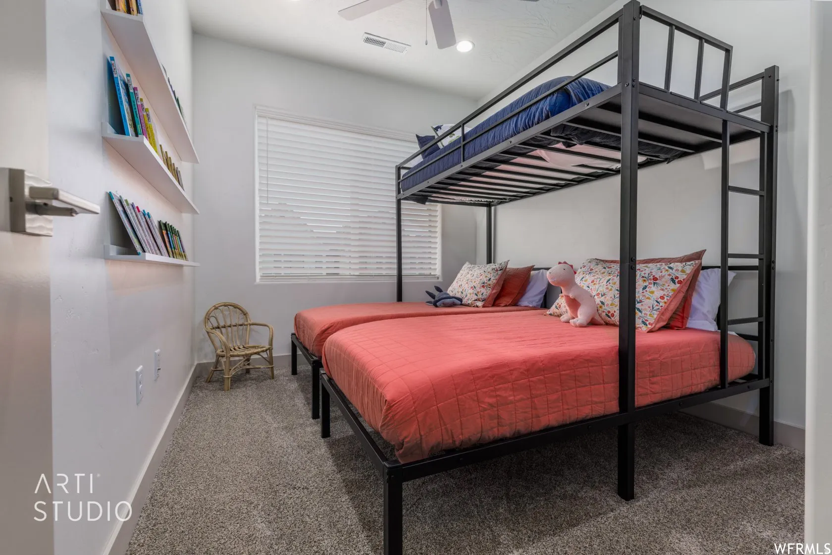 Carpeted room featuring a ceiling fan, window with blinds, and white floating shelves