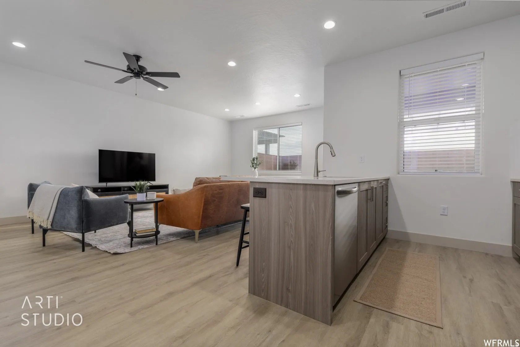 Open-concept living area with wood-finish flooring, recessed lighting, and a ceiling fan