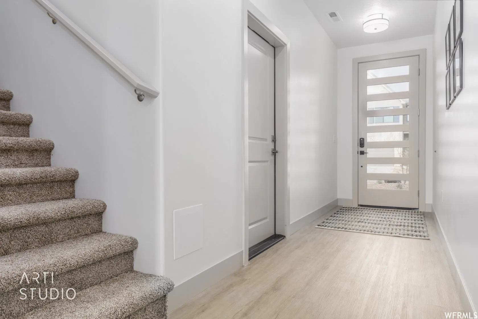 Entryway featuring light wood-finish flooring, a modern panel-style door with frosted glass inserts, and a contemporary flush-mount ceiling light