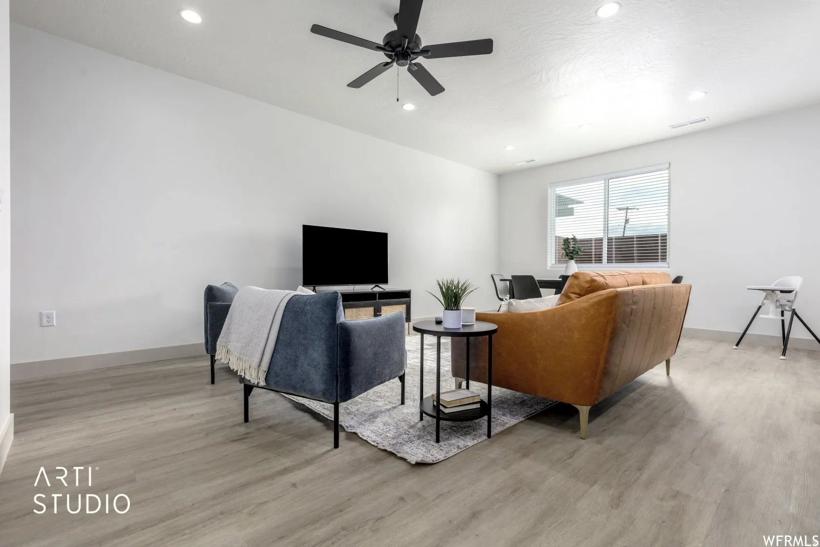 Open-concept living area featuring light wood-finish flooring, recessed lighting, and a contemporary ceiling fan