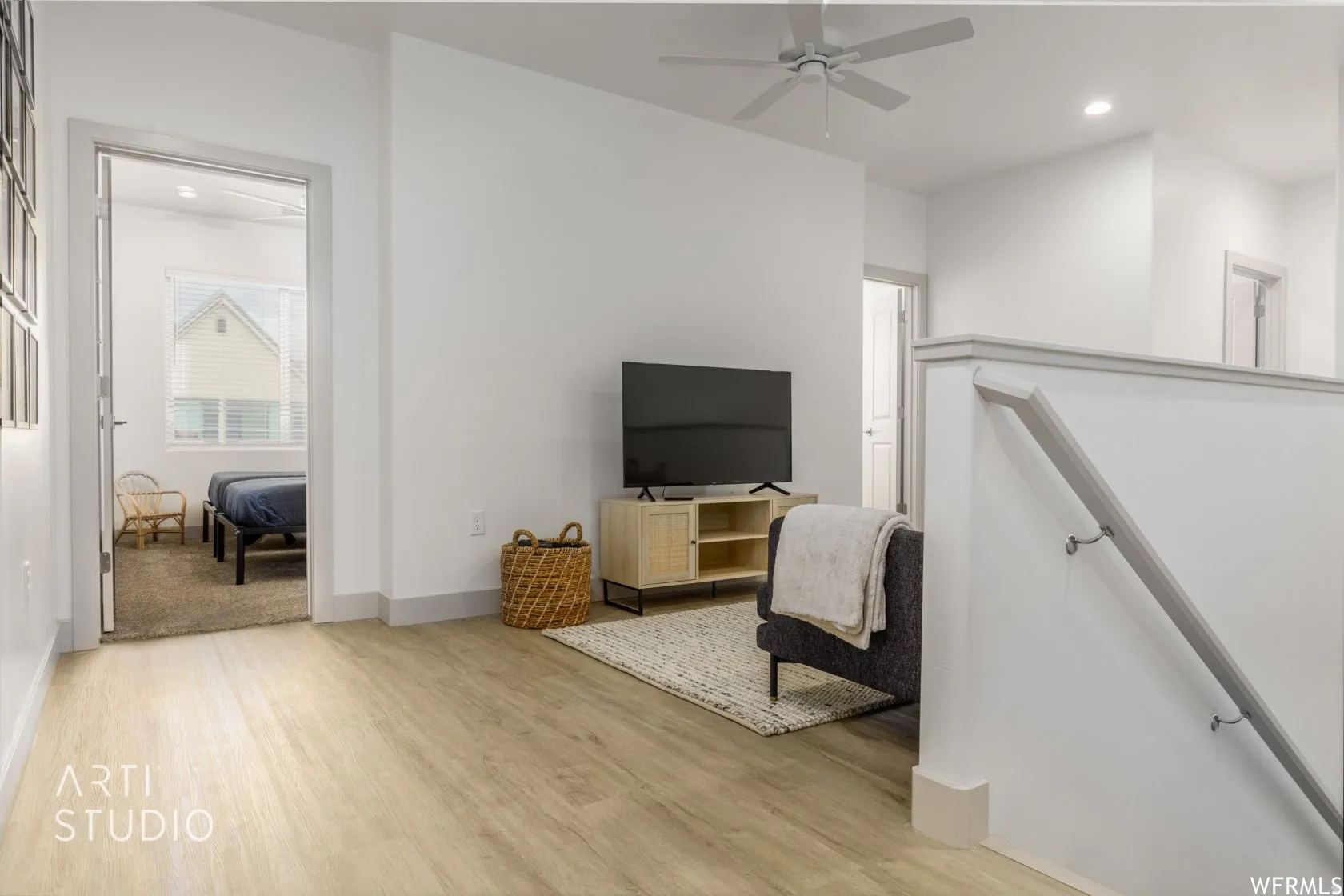Bright upper-level living area featuring light wood-finish flooring, recessed lighting, and a ceiling fan