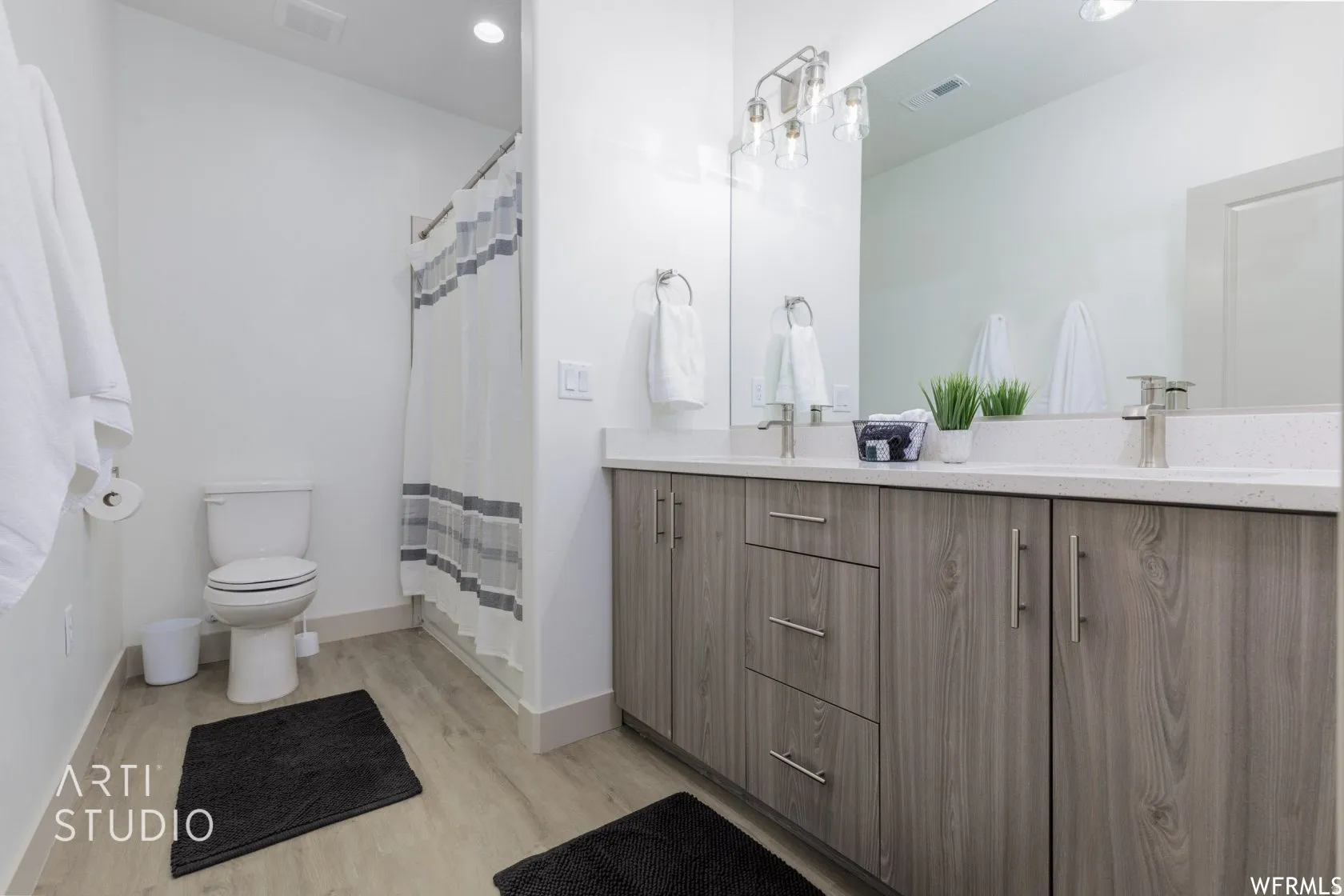 Double vanity with white countertop, chrome fixtures, and wood-finish cabinetry