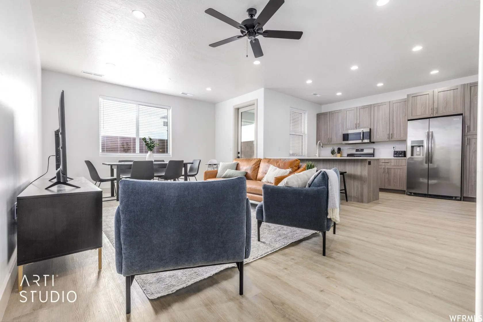 Open-concept living area featuring light wood-finish flooring, recessed lighting, and a contemporary ceiling fan