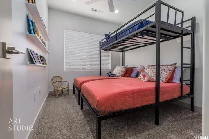 Carpeted room featuring a ceiling fan, window with blinds, and white floating shelves