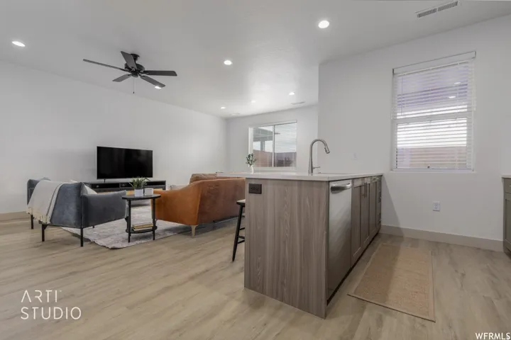 Open-concept living area with wood-finish flooring, recessed lighting, and a ceiling fan