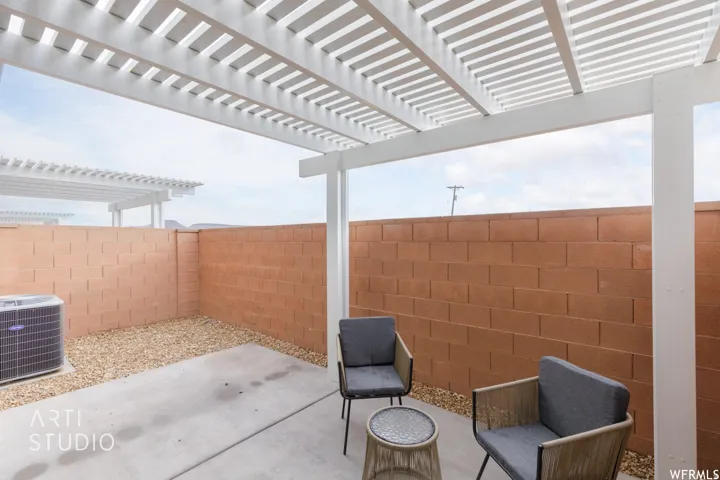 Outdoor patio featuring a white pergola, concrete flooring, and a gravel perimeter