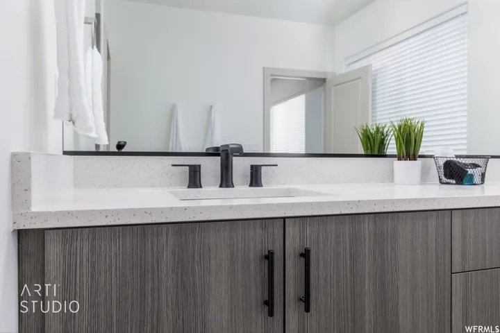 Bathroom vanity featuring a light speckled countertop, integrated rectangular sink, and matte black fixtures