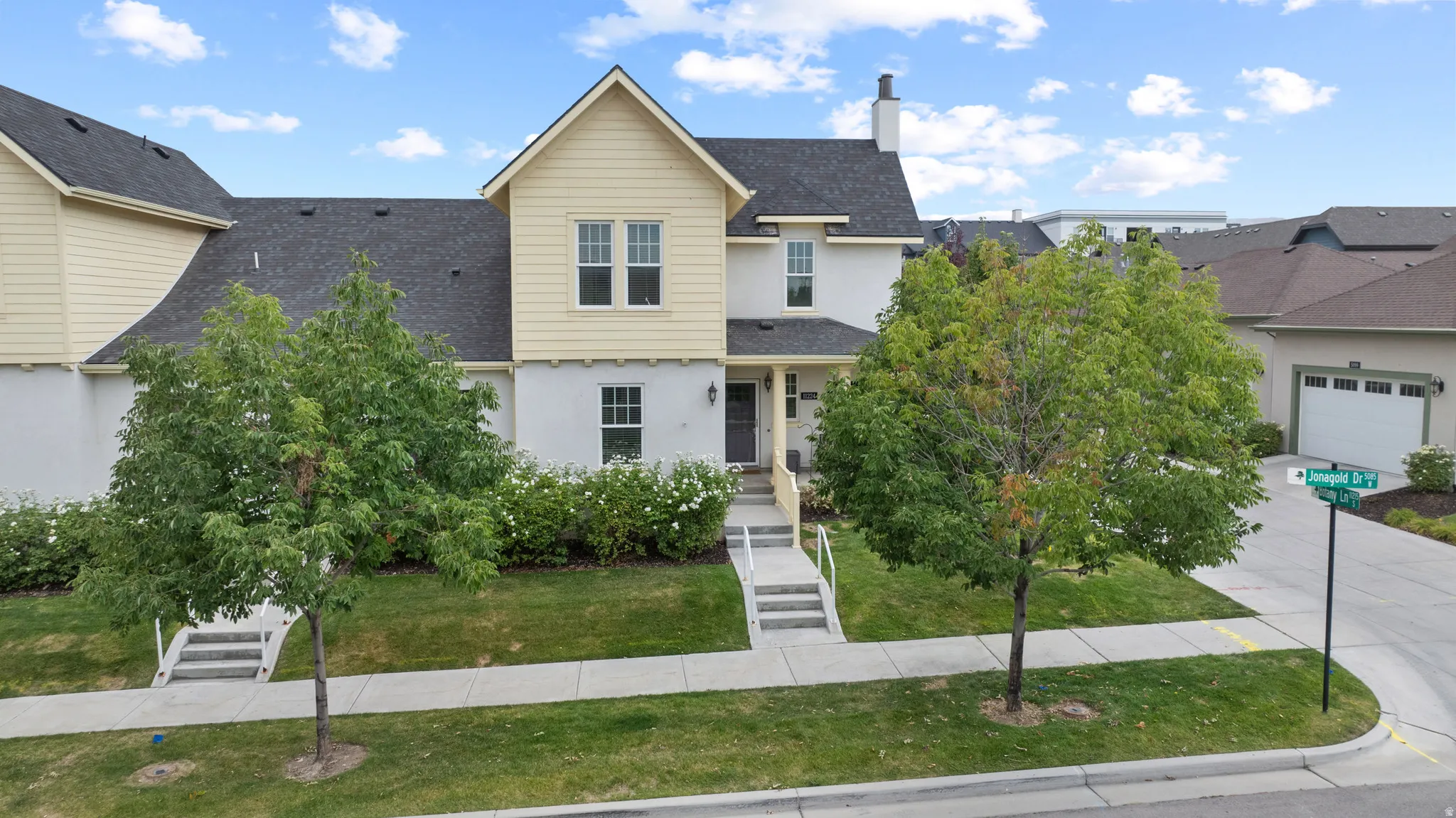 Multi-level residence featuring a prominent gable roofline and a blend of light-toned siding and stucco