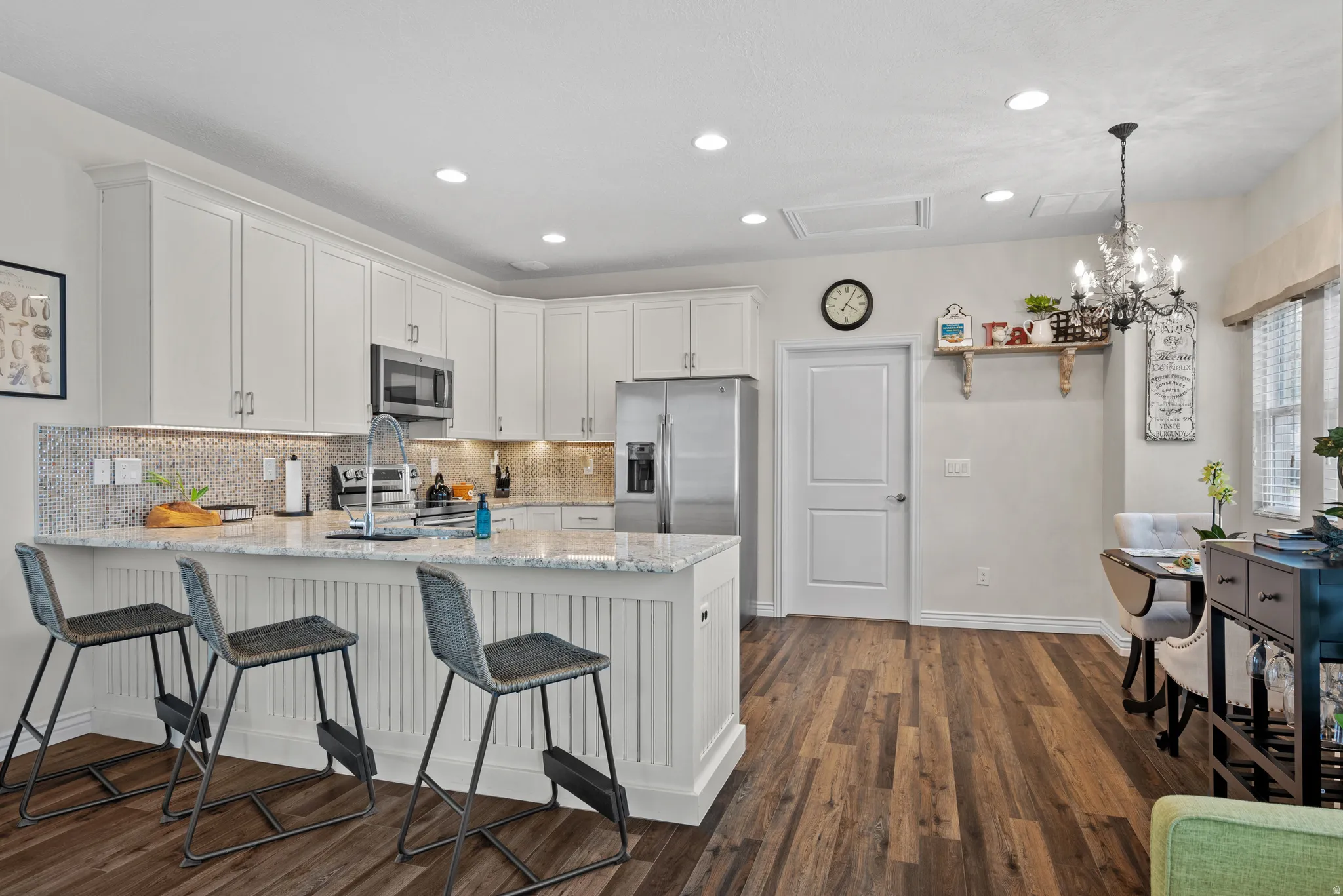 Kitchen featuring an island with white shaker paneling, a light-toned countertop, and an undermount sink with a gooseneck faucet