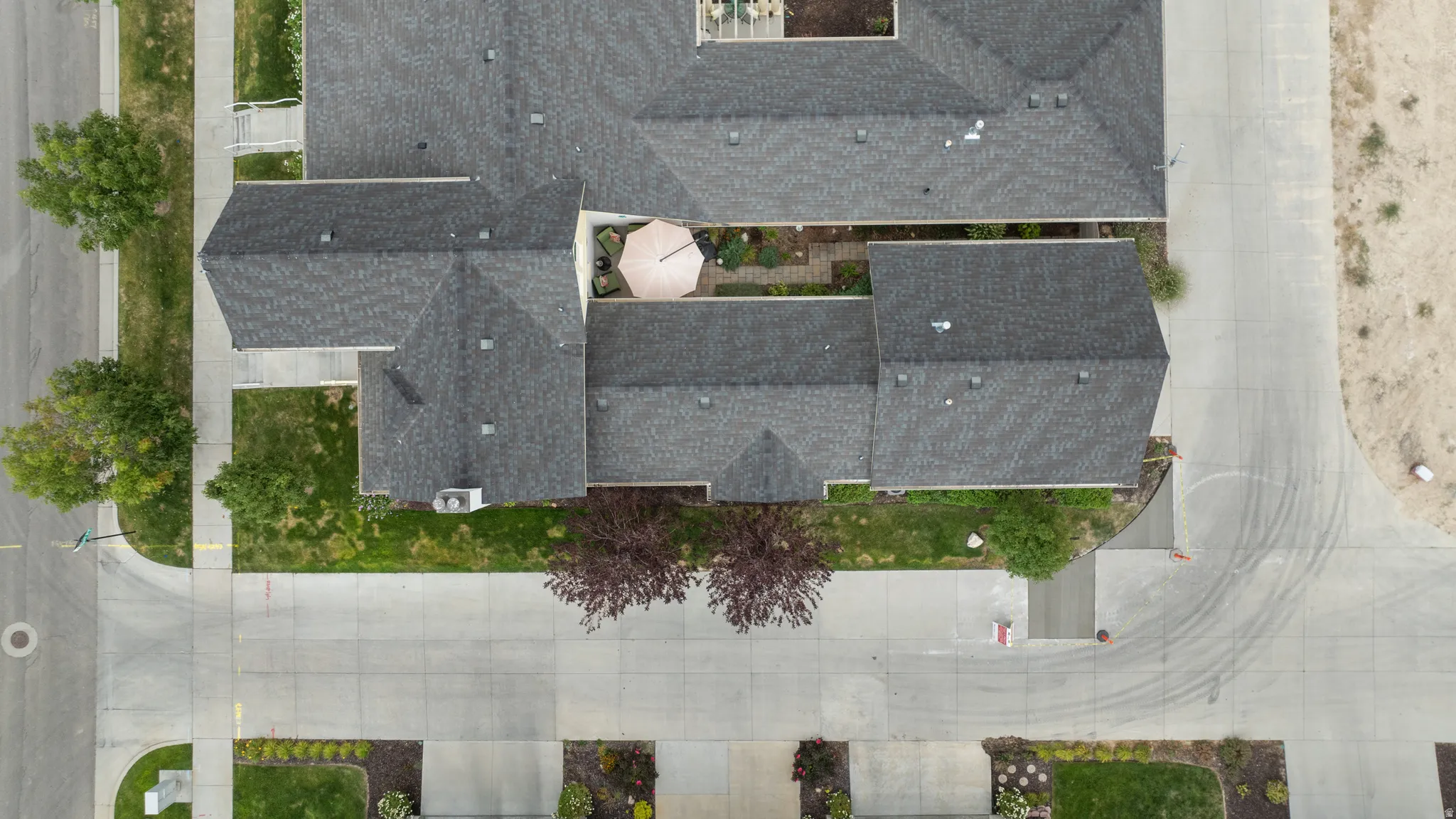 Aerial perspective showcasing the property's composite shingle roofing, paved driveways, and courtyard patio