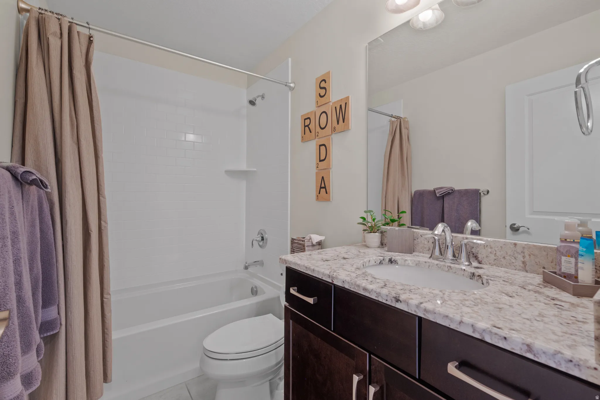 Bathroom featuring a single vanity with stone-finish countertop, undermount sink, and dark wood-finish cabinetry