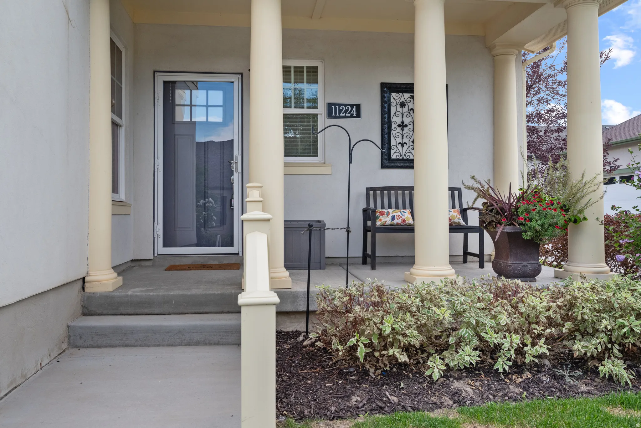 Covered front porch featuring cream-colored columns and a concrete entry