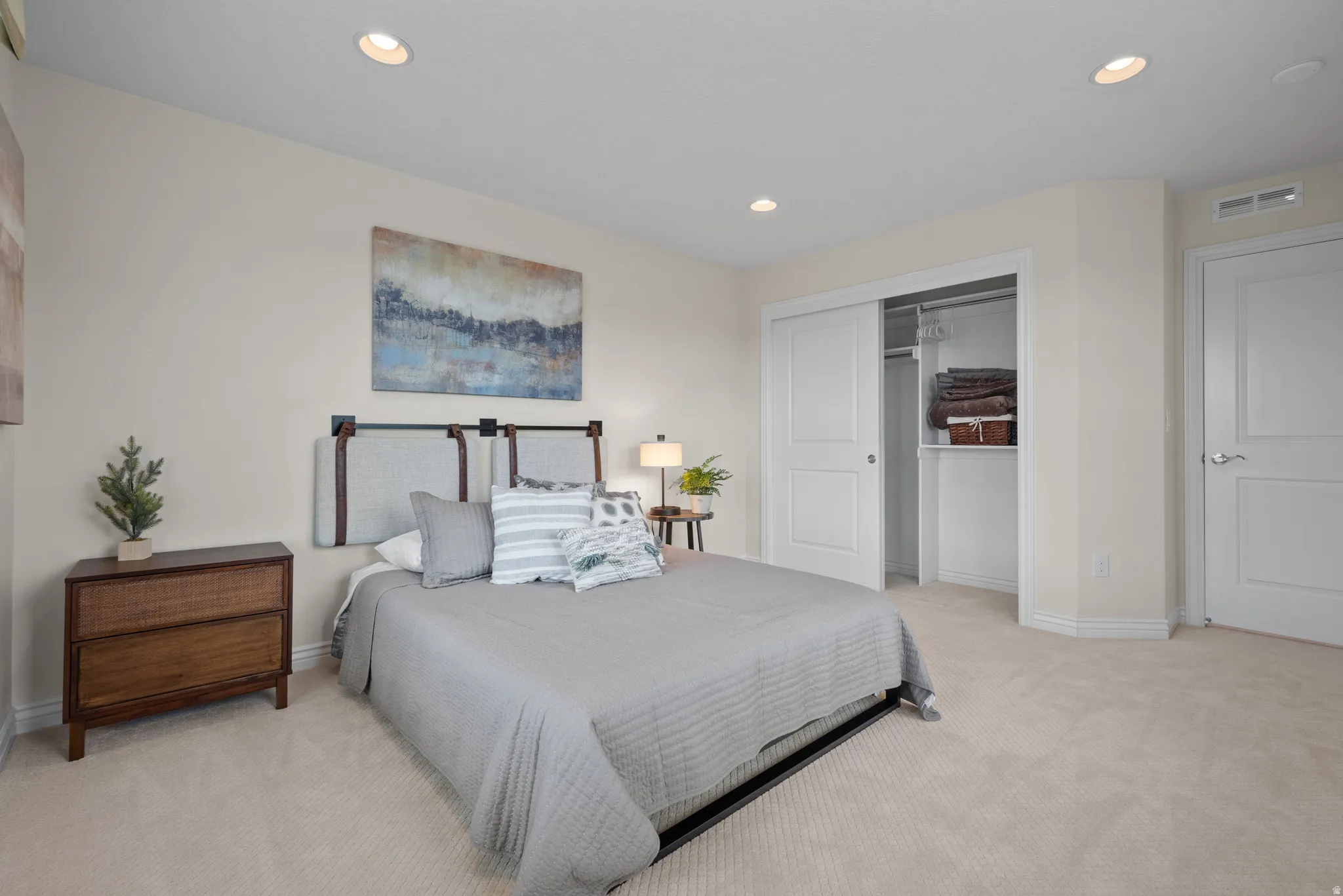 Recessed ceiling lighting illuminates a room featuring light-toned carpeting and a closet with white bi-fold doors