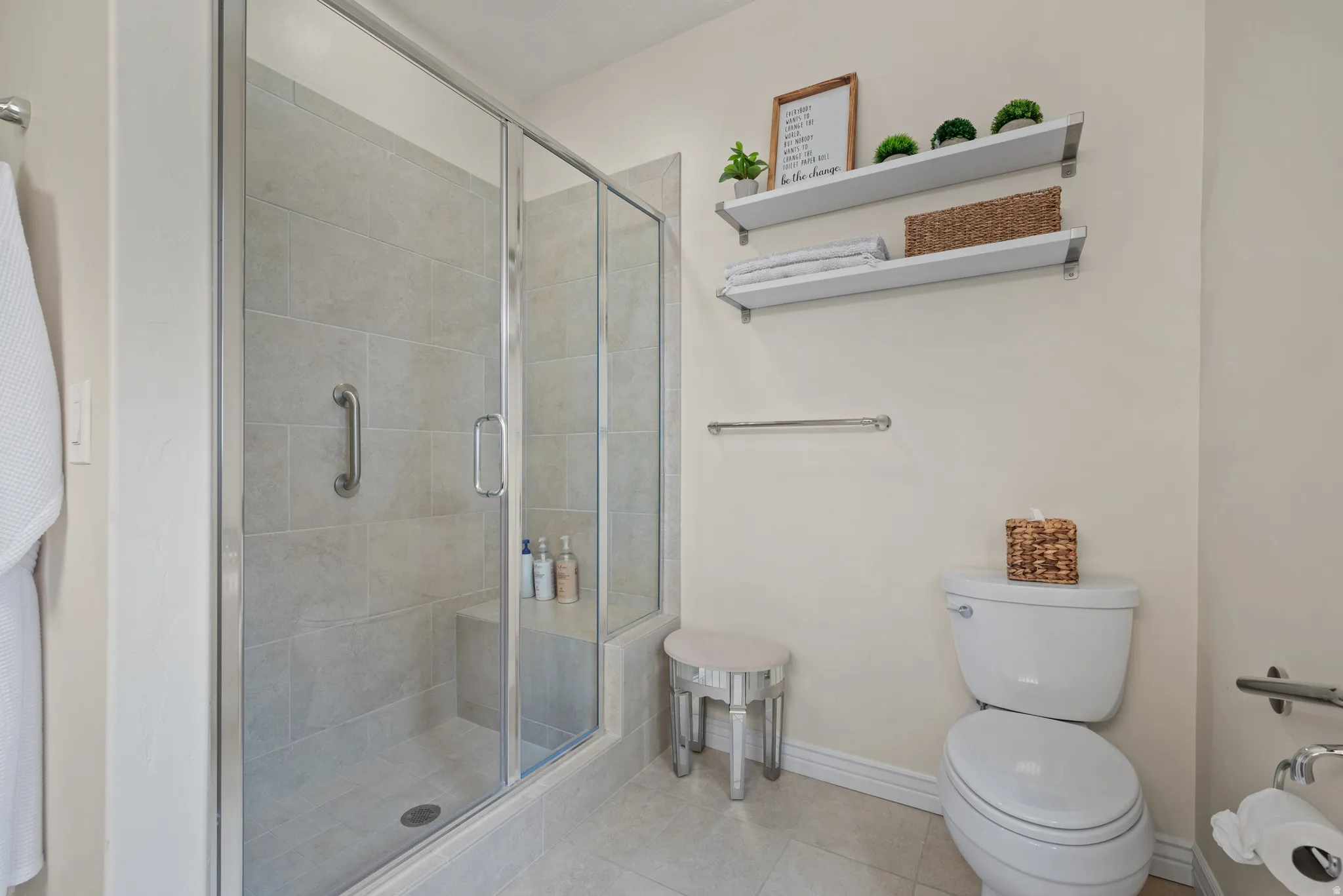 Walk-in shower with clear glass enclosure and tile surround