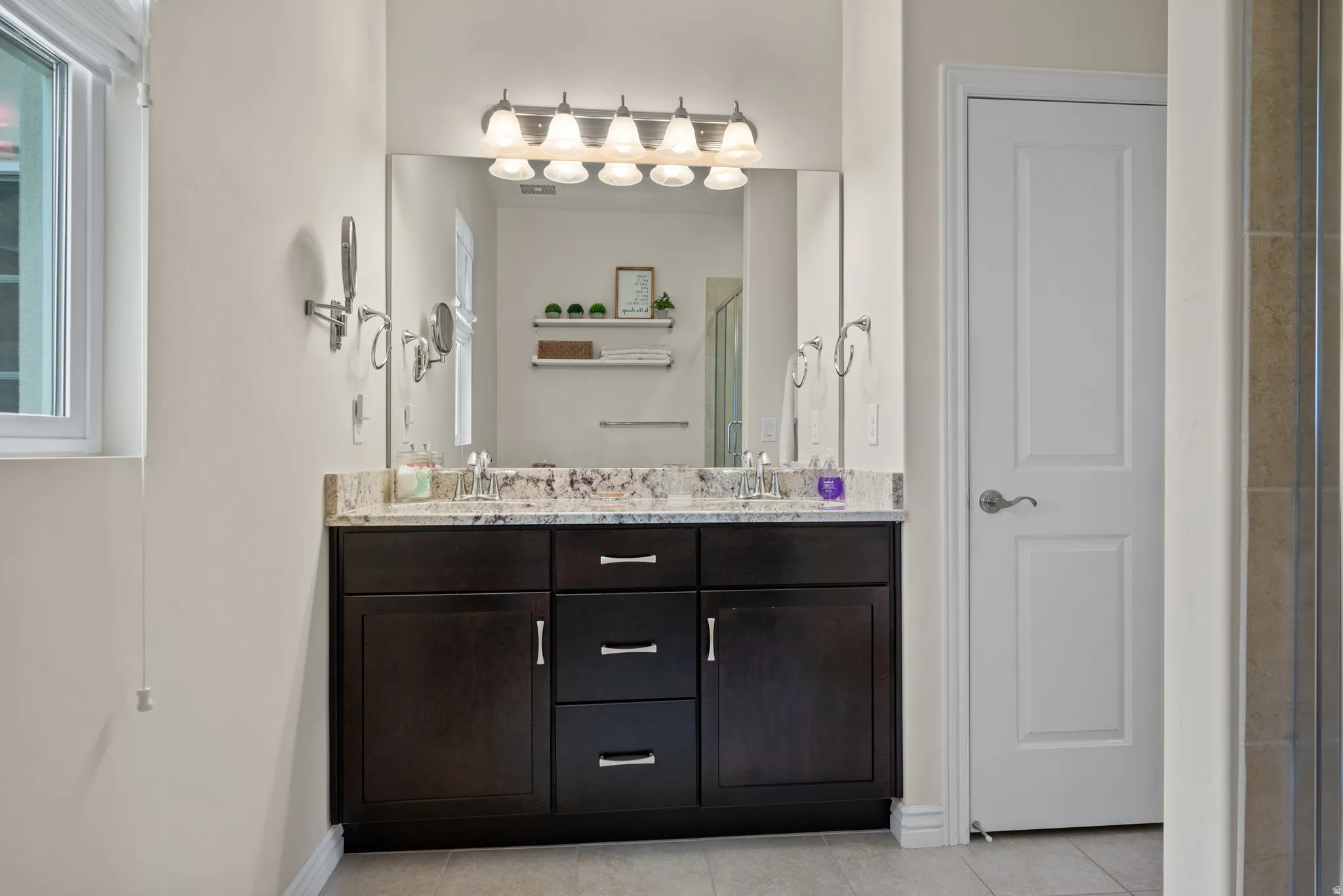 Double vanity with a granite countertop, dual undermount sinks, and a dark wood-finish cabinet