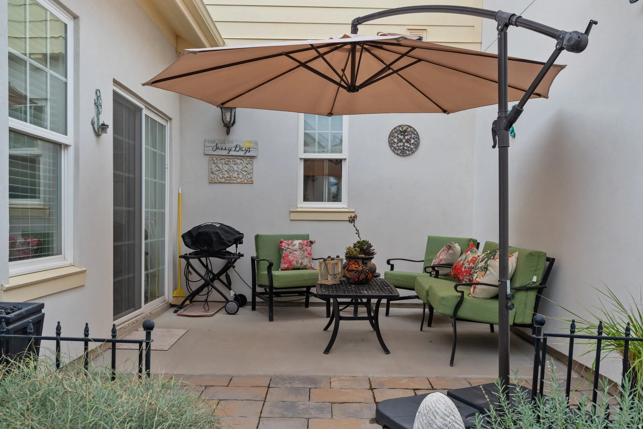 Private outdoor patio featuring a concrete slab, paver stone border, and stucco exterior walls