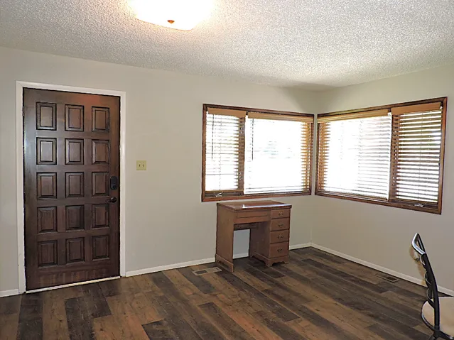 Entryway featuring a paneled wood door and wood-finish flooring