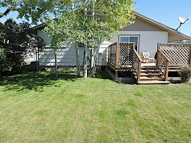 Expansive green lawn with a wood deck featuring lattice railing