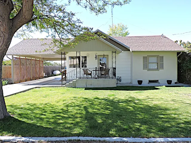 Front exterior featuring a covered porch with decorative railing, a paved driveway, and an attached carport